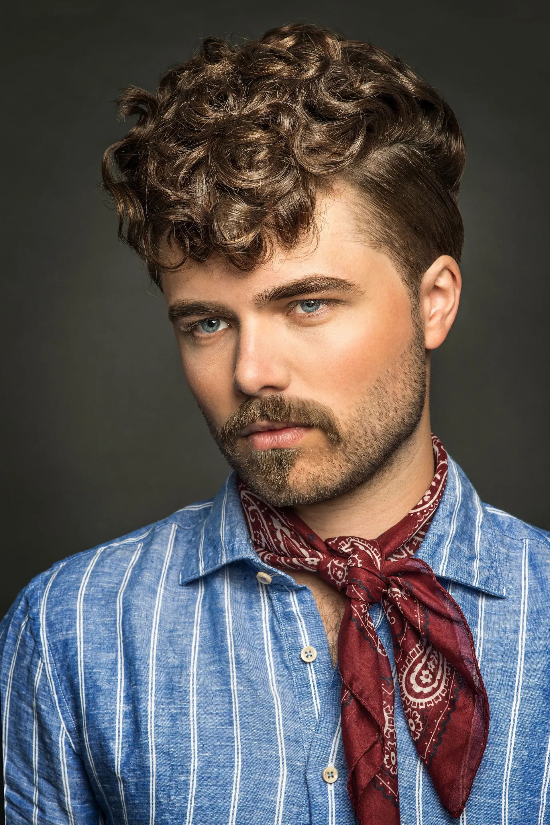 Peinado masculino rizado con degradado taper y volumen natural – corte de caballero profesional en CUTS&CUPS Barbershop, Varberg.