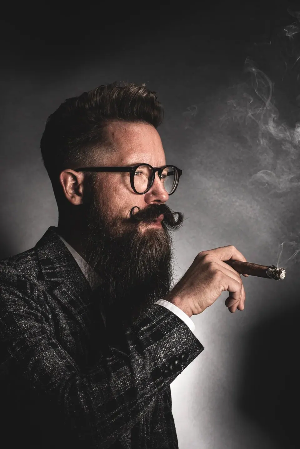 Degradado a piel con el pelo peinado hacia atrás y barba bien recortada – corte de caballero profesional en CUTS&CUPS, Varberg.